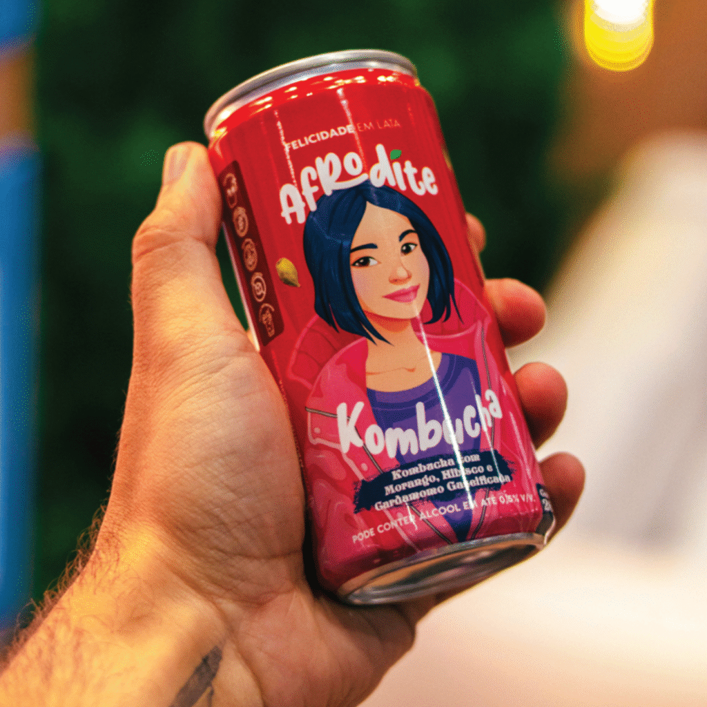 Sleeve colorido da bebida Afrodite Kombucha em lata vermelha, ilustrado com personagem feminina estilizada.