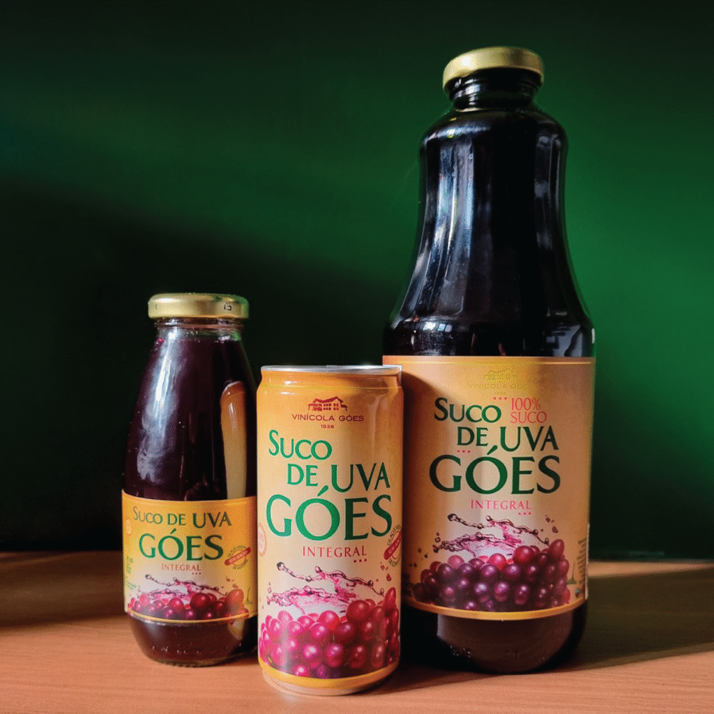Rótulos do Suco de Uva Góes Integral em diferentes embalagens, incluindo garrafa de vidro, lata e PET, destacando cores dourado e roxo.